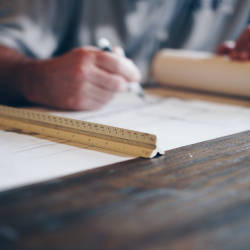 Person writing on construction plans.
